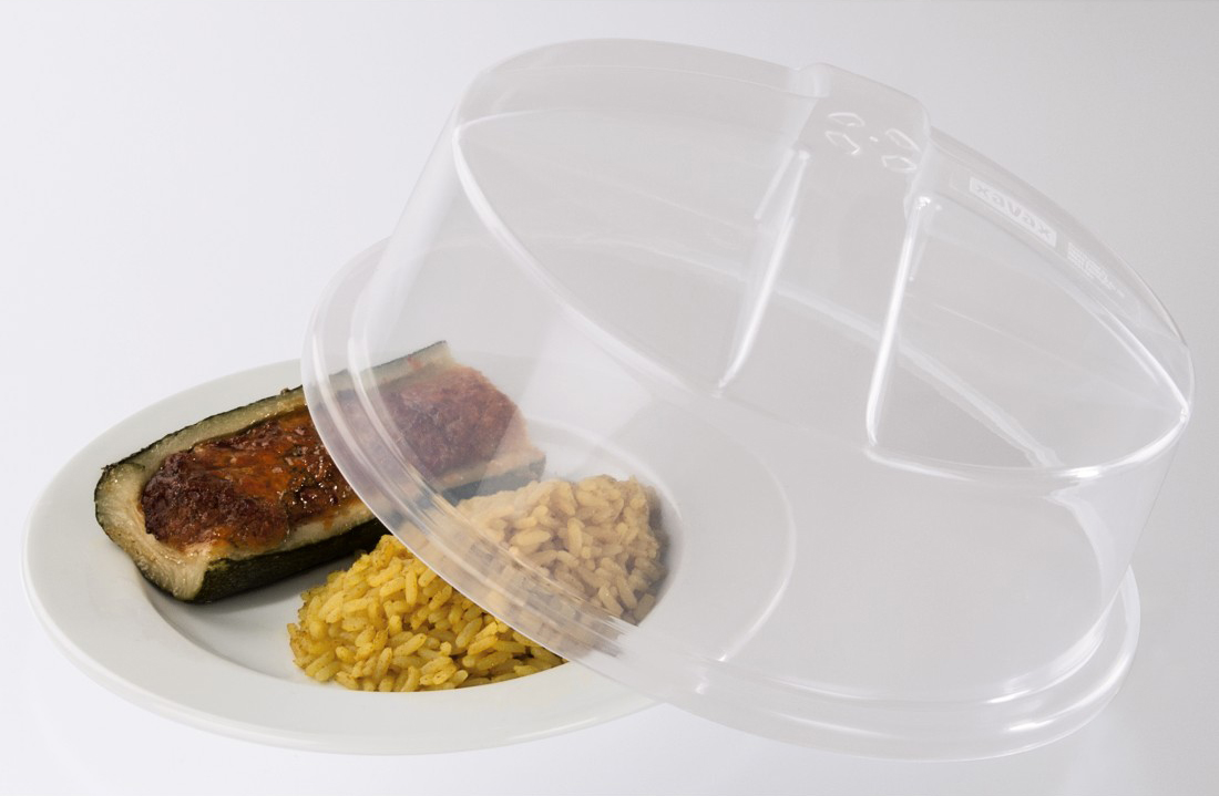 Een bord met eten ligt onder een doorzichtige plastic deksel. Er is courgette, rijst en een ander voedselitem.