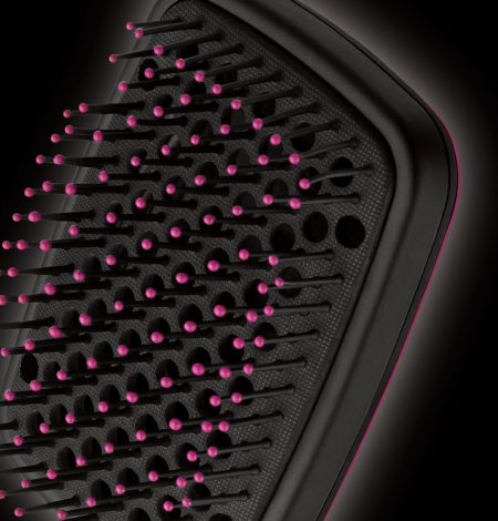 Schwarze Haarbürste mit rosa Borsten. Nahaufnahme der Borsten vor dunklem Hintergrund.
