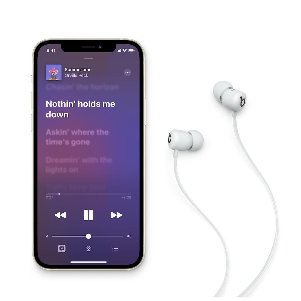 Ein Smartphone mit einer Musik-App und Ohrhörern daneben auf Weiß.
