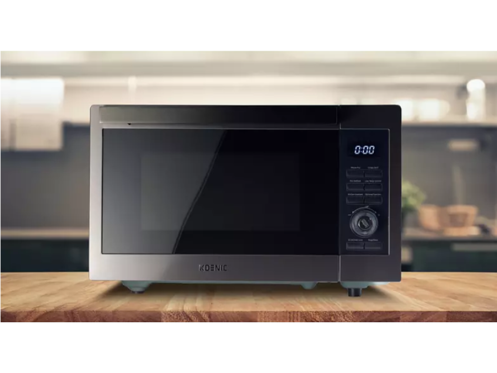 Un microondas negro sobre una superficie de madera. El fondo es una cocina.