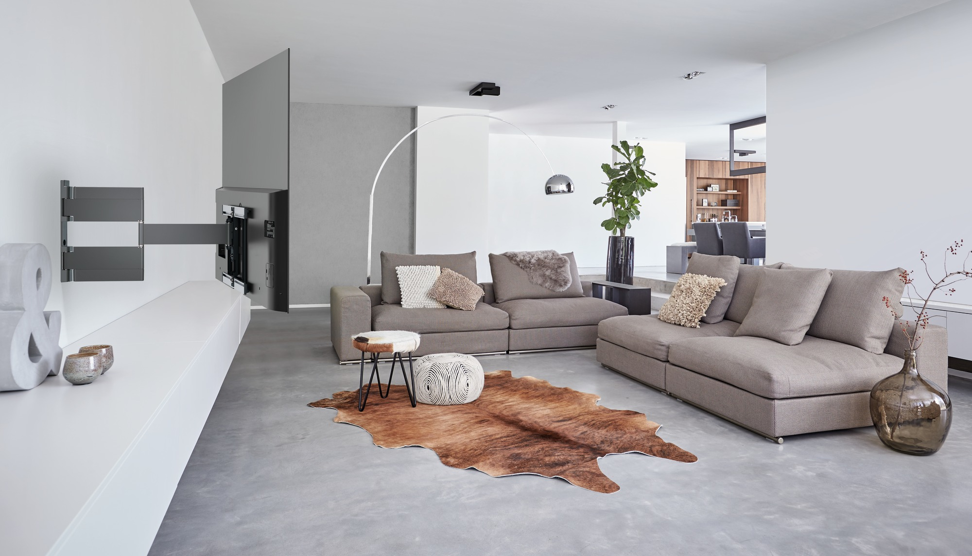 Ein modernes Wohnzimmer mit großem Sofa, Lederteppich und Wand-TV.
