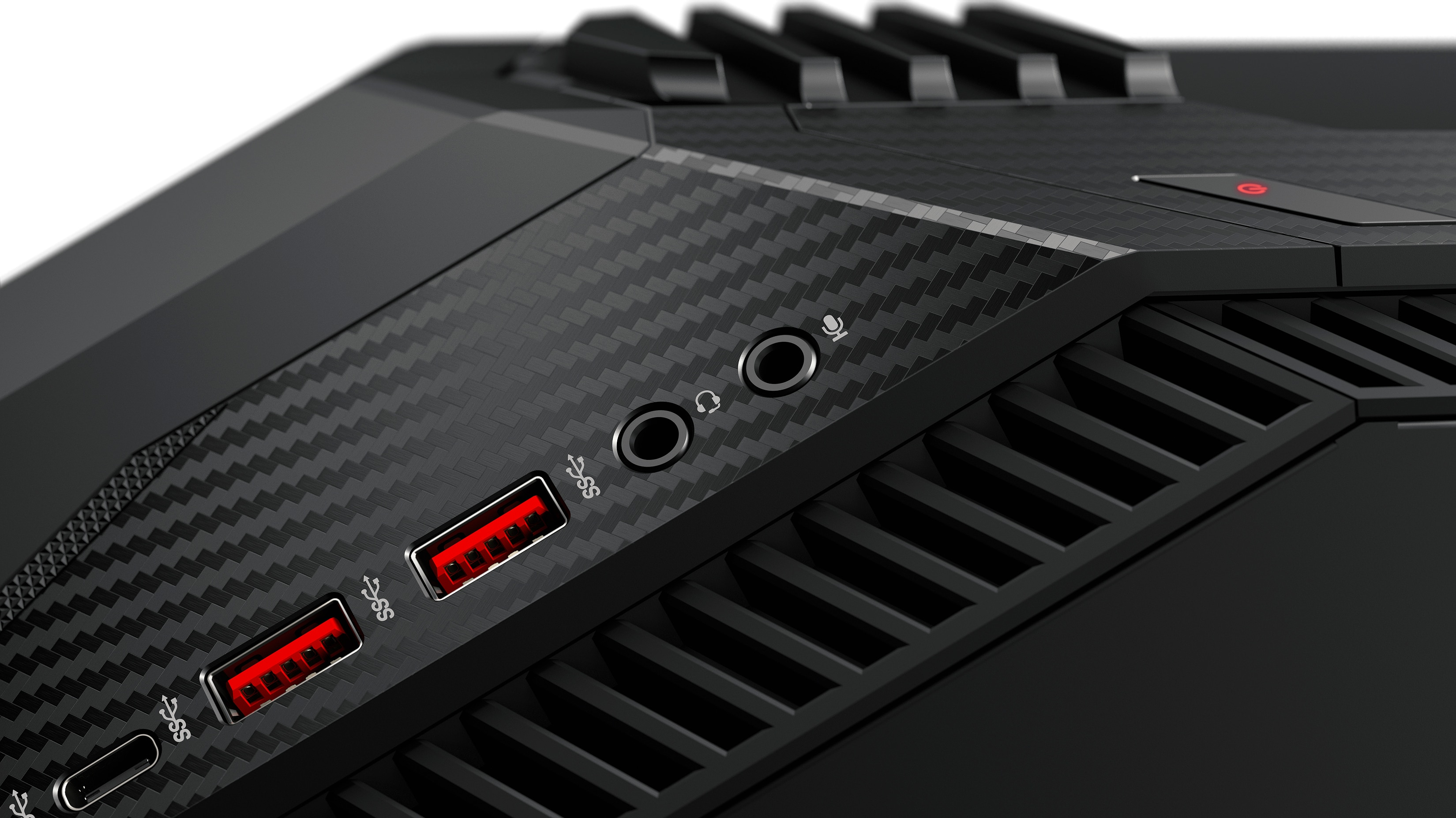 Nahaufnahme eines schwarzen Geräts mit USB-Anschlüssen, Audio- und Mikrofonbuchsen und einem Karbonfaser-Design.