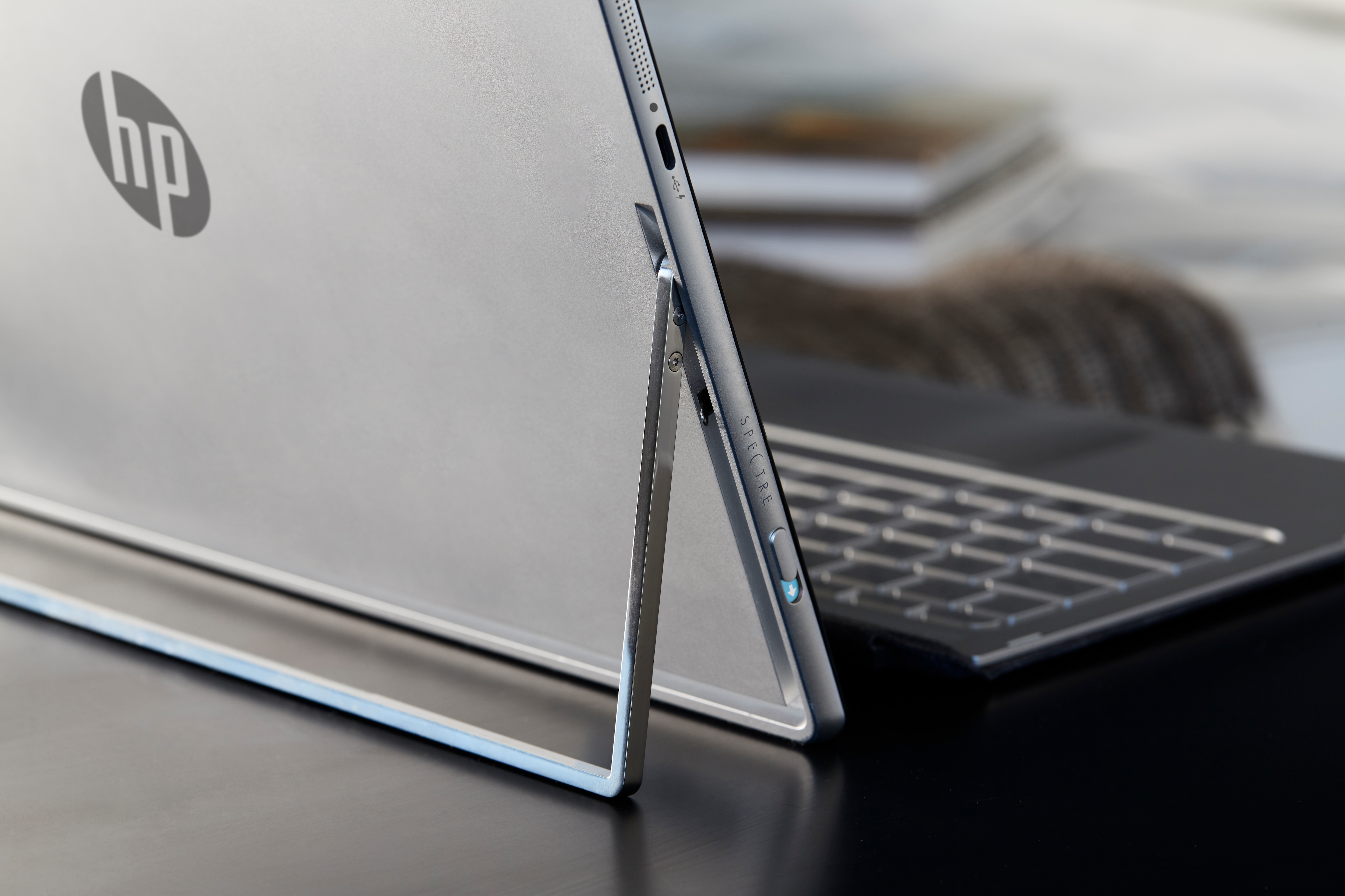 Rückseite eines silbernen HP Spectre Laptops mit integriertem Ständer auf einem Tisch.