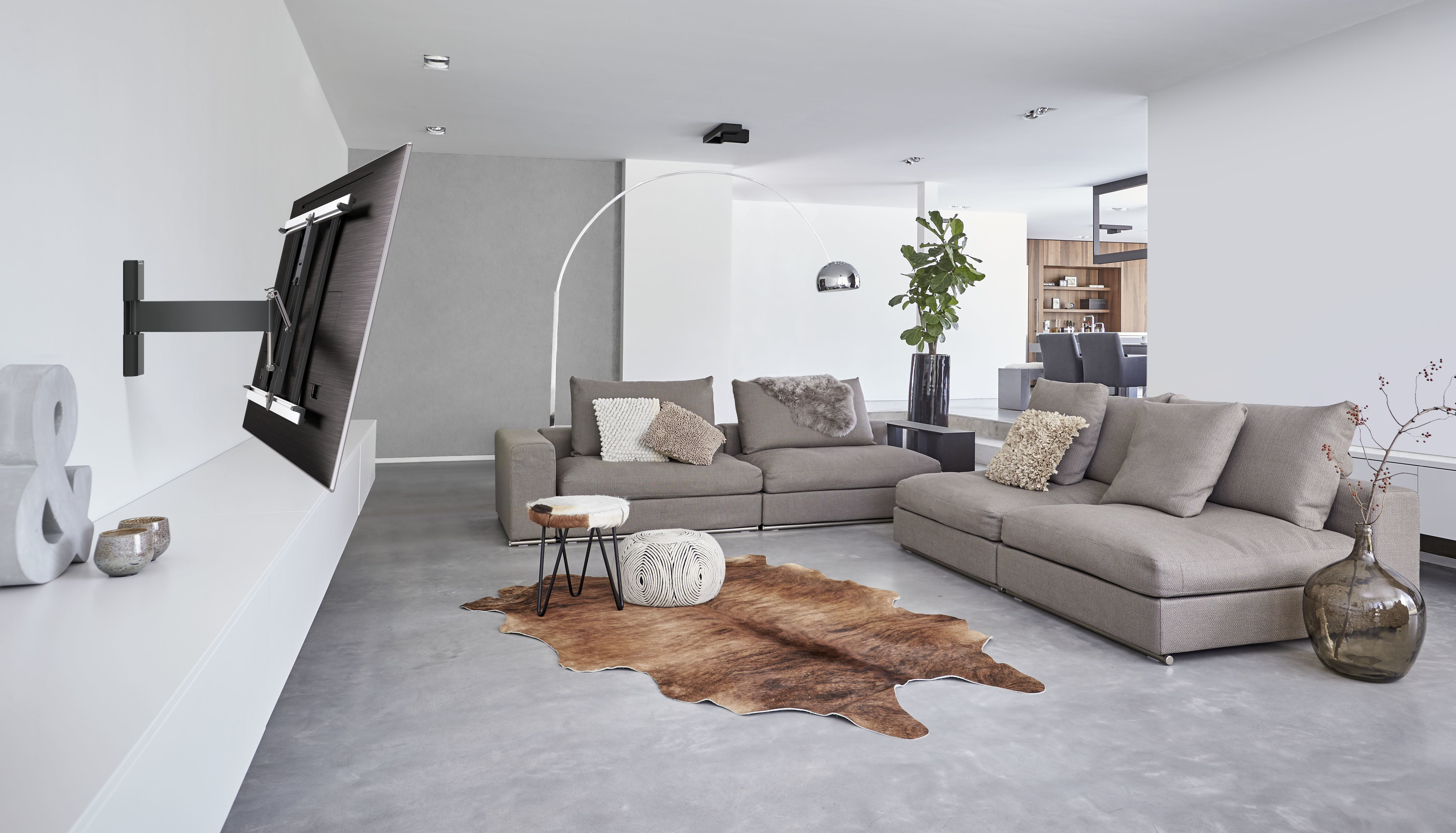 Ein modernes Wohnzimmer mit einem an der Wand montierten Fernseher und einem braunen Teppich.
