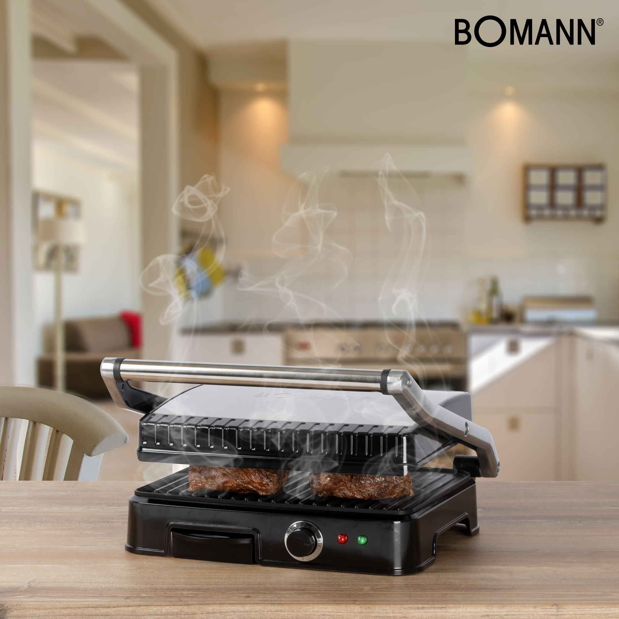 Ein Bomann-Grill mit zwei Steaks, sichtbarem Dampf, auf einem Holztisch mit Küchenhintergrund.