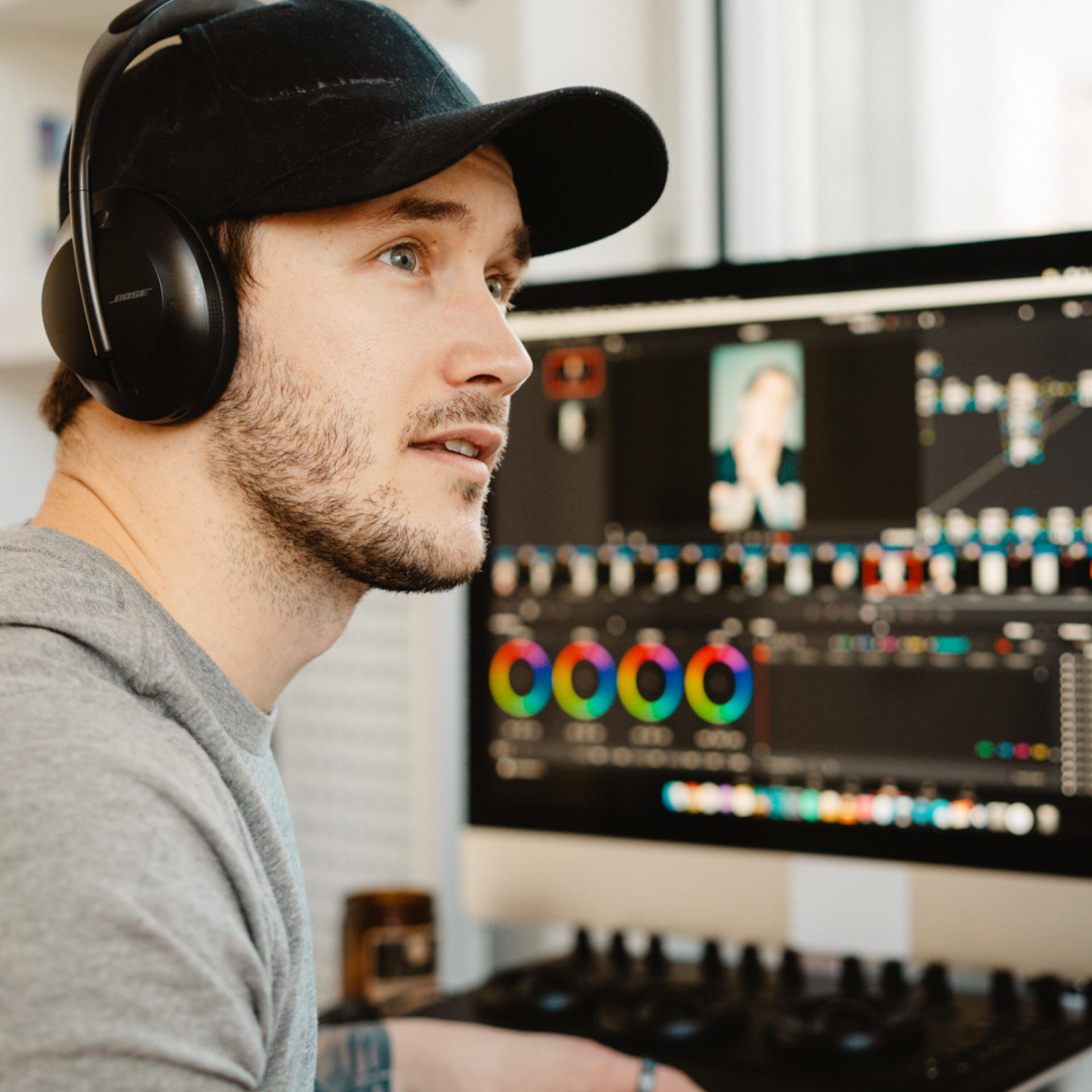 Mann mit Kopfhörern, blickt auf einen Computerbildschirm. Bildschirm zeigt Videobearbeitungsprogramm.