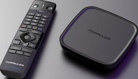 Box TV Formuler nero e telecomando, su una superficie grigia. Telecomando con pulsanti.