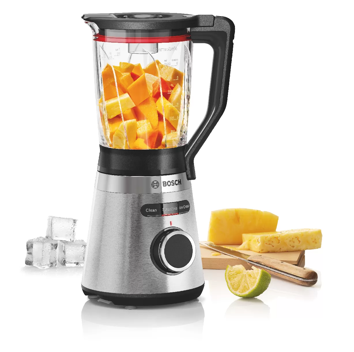 Een blender gevuld met gesneden mango's en ander fruit, met ijsblokjes en een limoen ervoor. Bosch-logo zichtbaar.