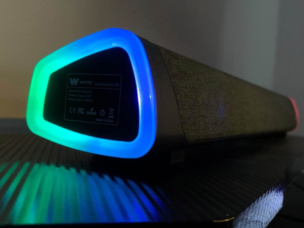 Altavoz negro y gris con luces azules, verdes y rojas. Tiene una etiqueta.