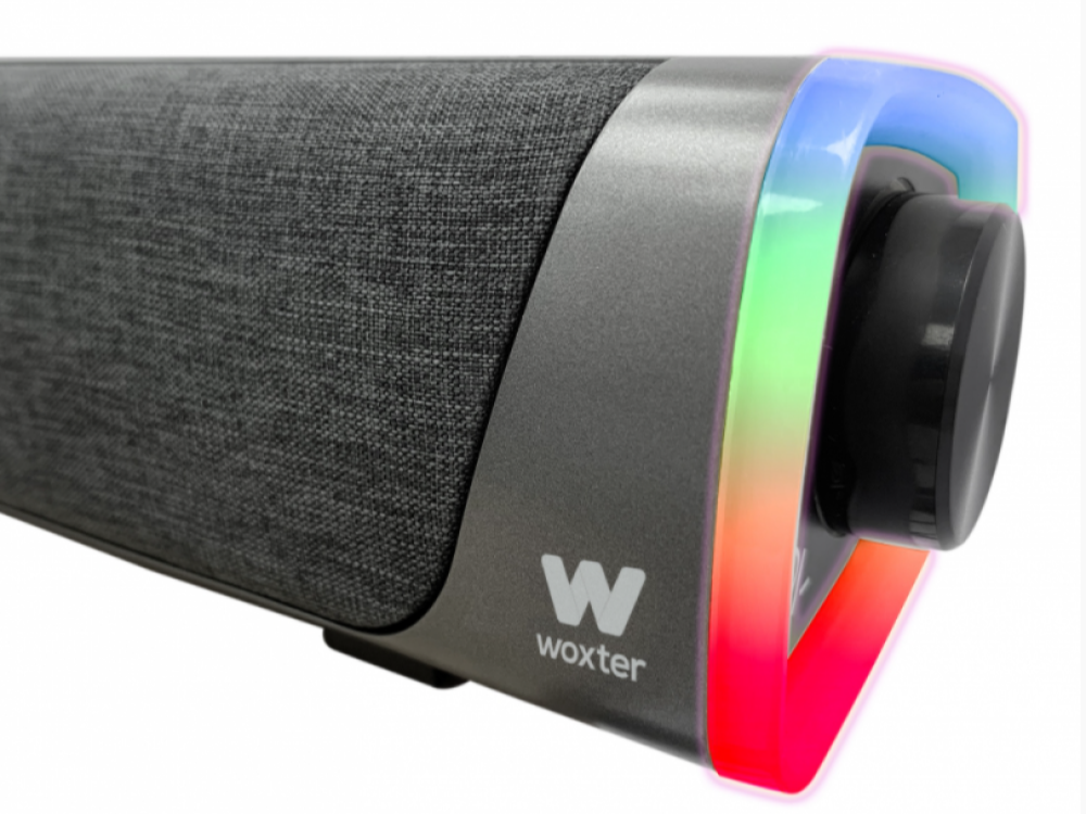 Un altavoz gris con el logotipo de Woxter y un mando de volumen. Los extremos tienen luces de colores.
