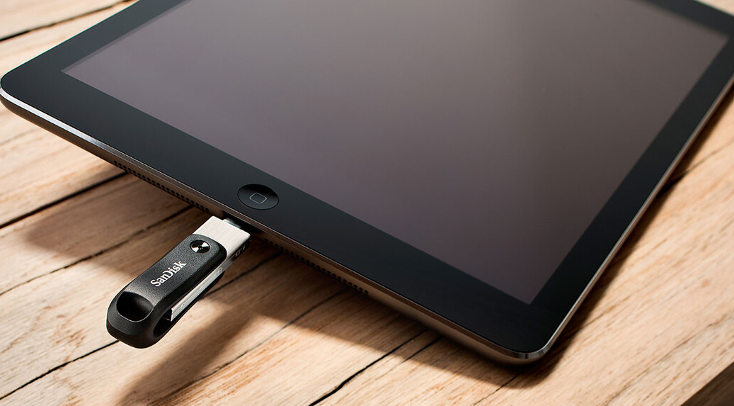 iPad nero con una chiavetta USB collegata su una superficie in legno.