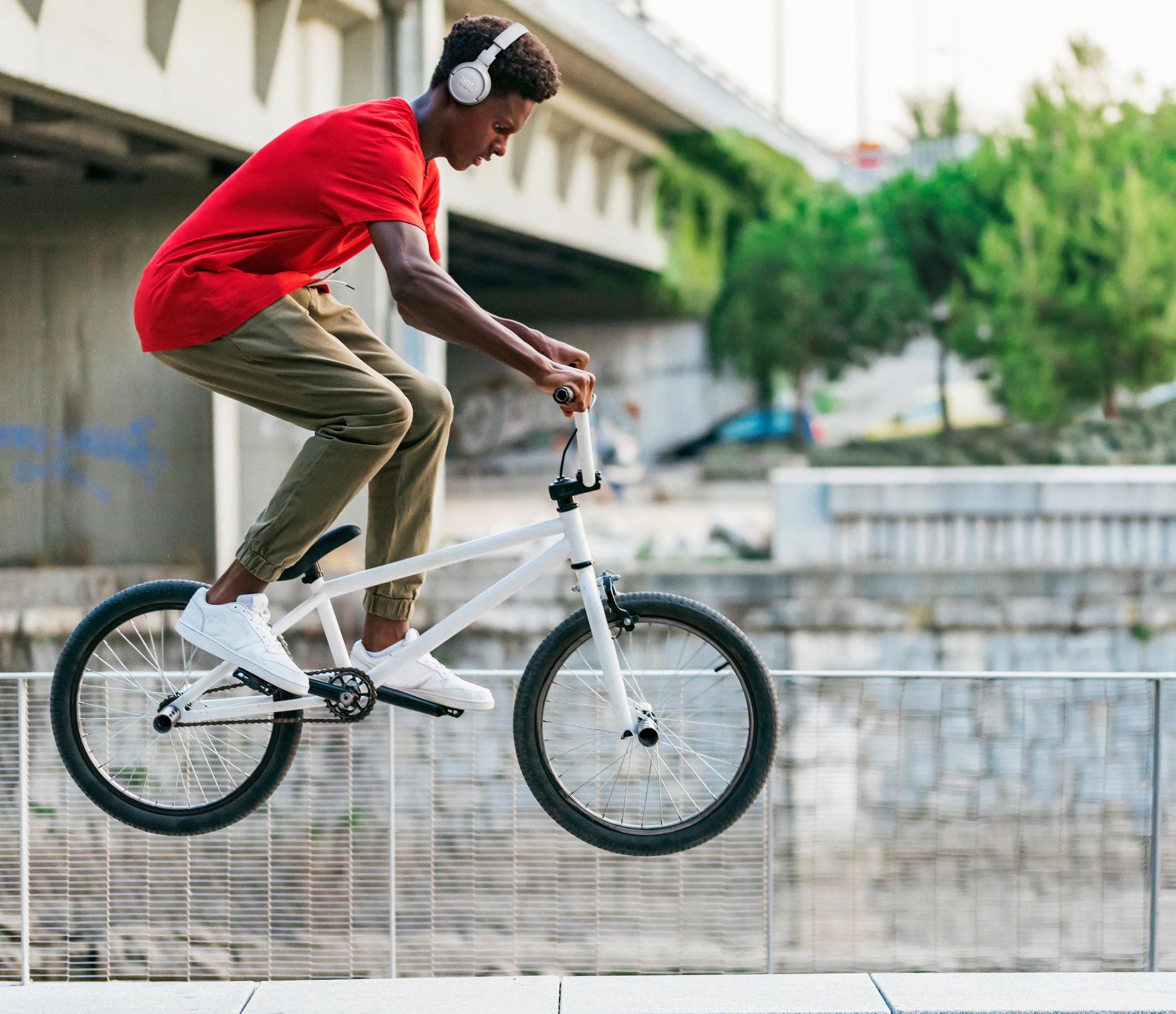 Ein junger Mann auf einem BMX-Rad in der Luft, mit Kopfhörern.