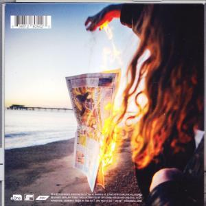 Albumcover mit brennender Zeitung am Strand bei Sonnenuntergang. Eine Person hält das Papier.