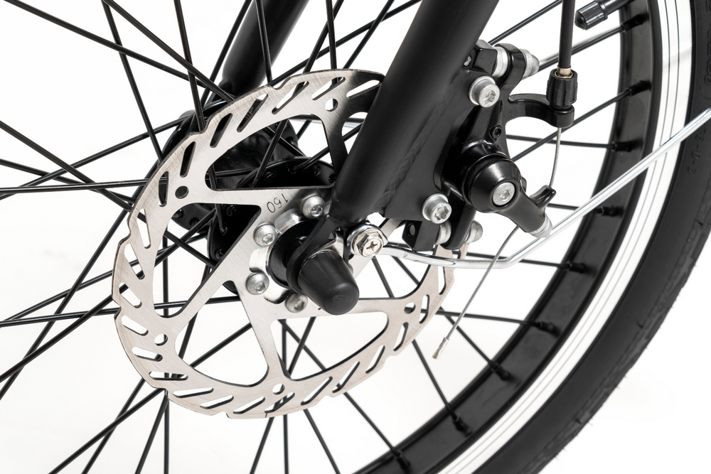Primer plano de un freno de disco y rueda de bicicleta, con radios negros.