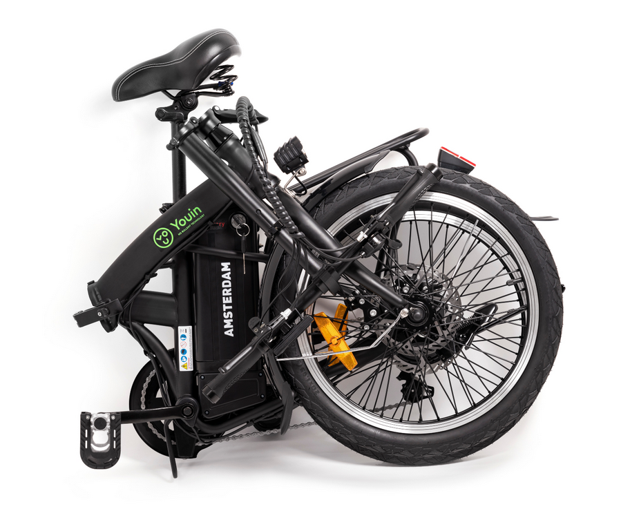 Bicicleta eléctrica negra plegada, fondo blanco. Marca 'Youin' visible.