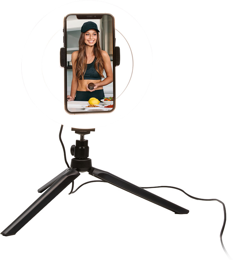 Een vrouw met eten op een telefoonscherm, in een ringlicht. Een statief houdt de telefoon vast. Witte achtergrond.