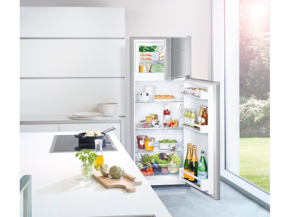 Una cocina con refrigerador abierto y encimera. Luz solar brillante brillando.
