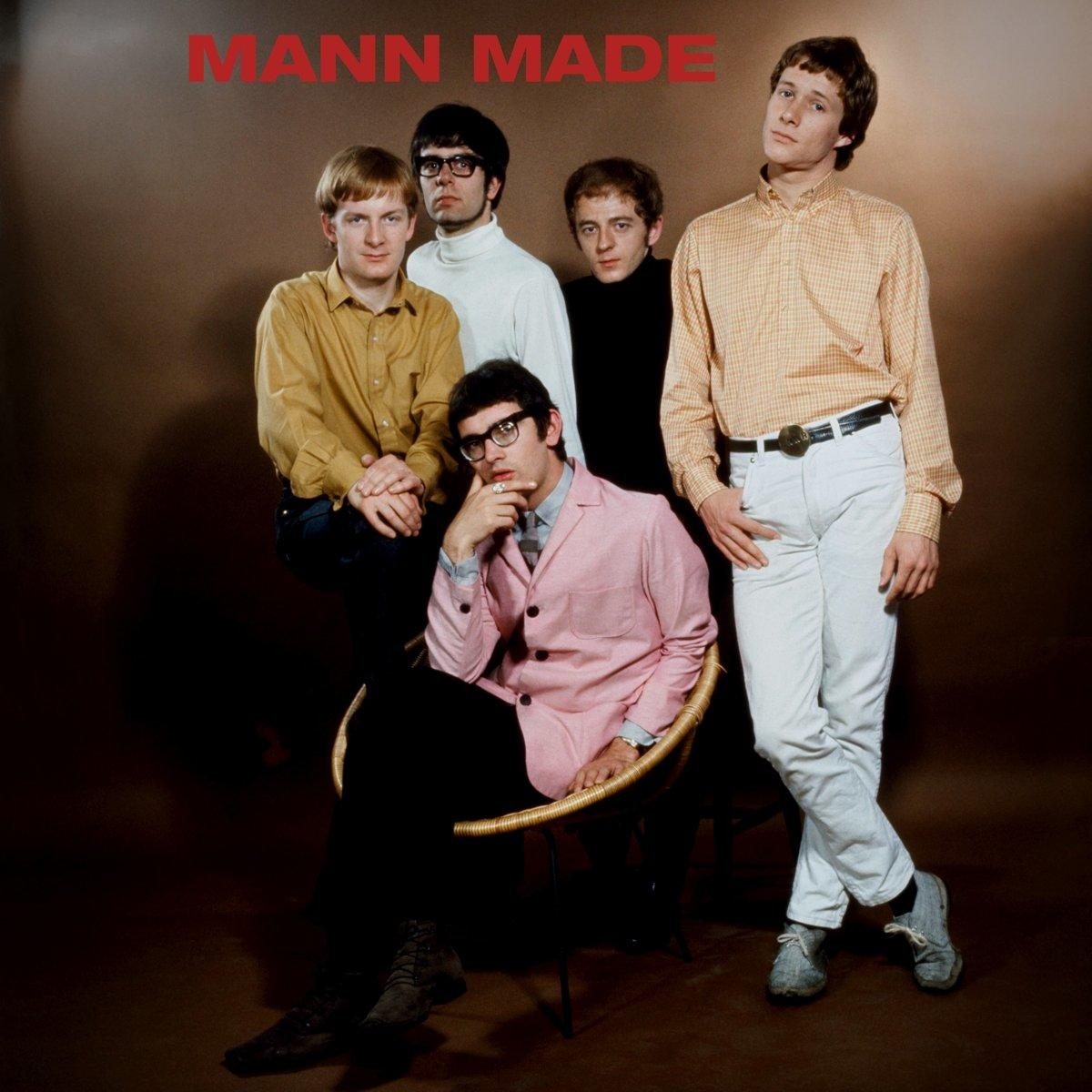 Bandfoto von Mann Made. Fünf Männer, einige in Rollkragenpullovern, posieren vor braunem Hintergrund.
