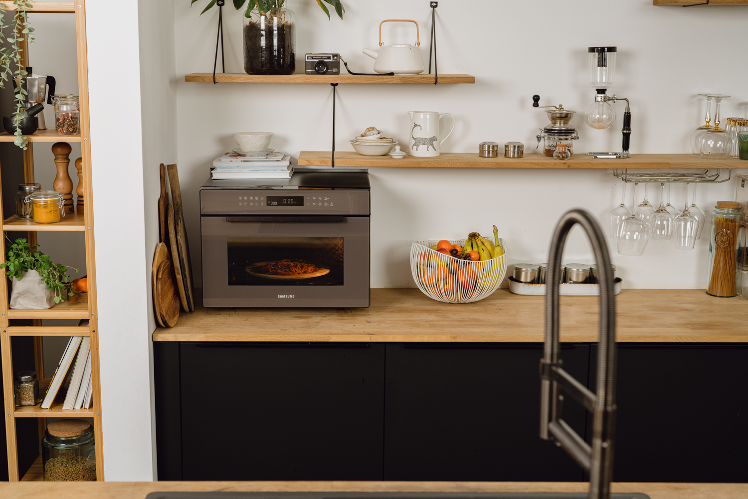 Een moderne keuken met een oven, planken en een fruitschaal.