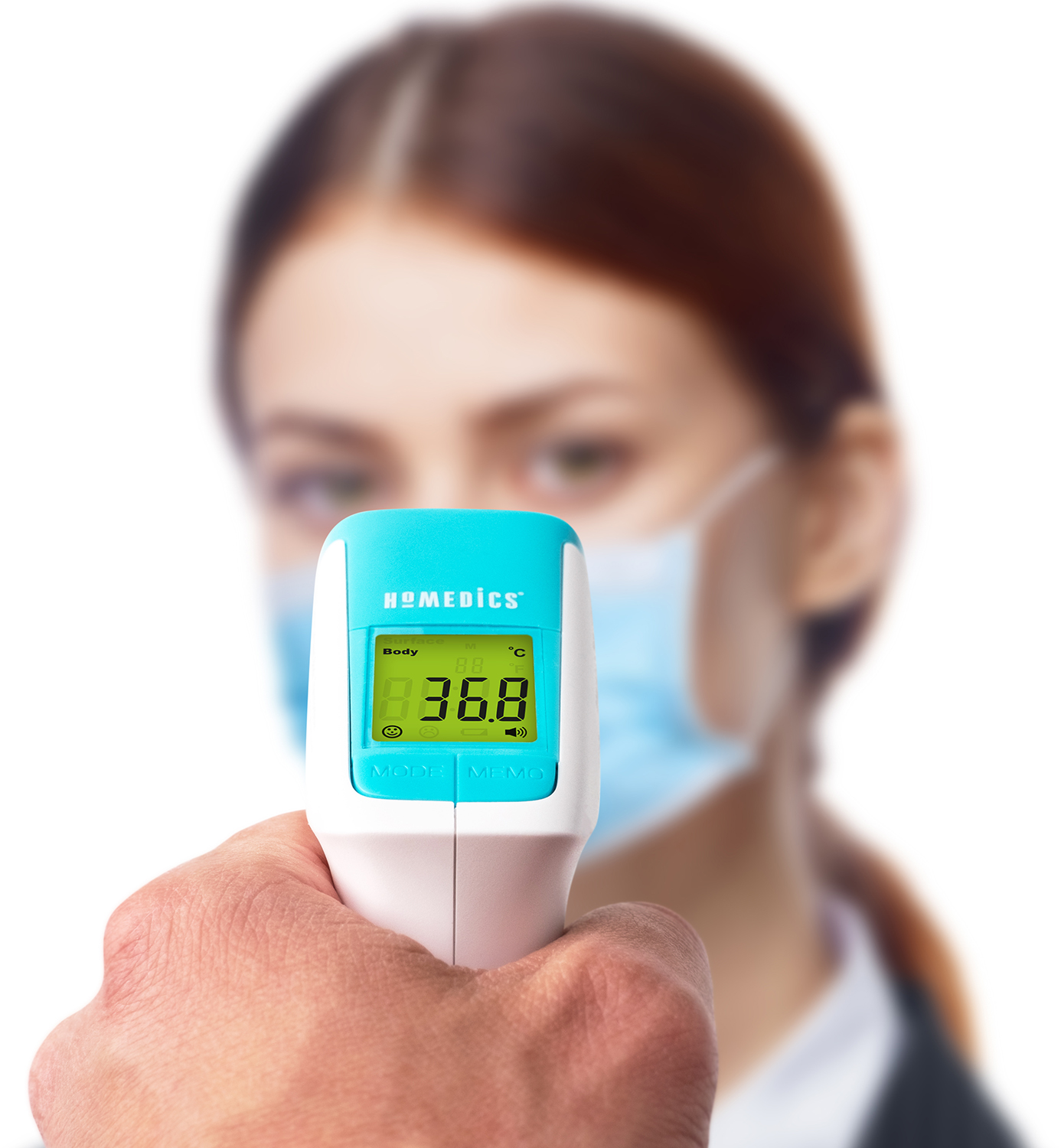 A person holding a digital thermometer, with a blurred background of a woman wearing a mask.