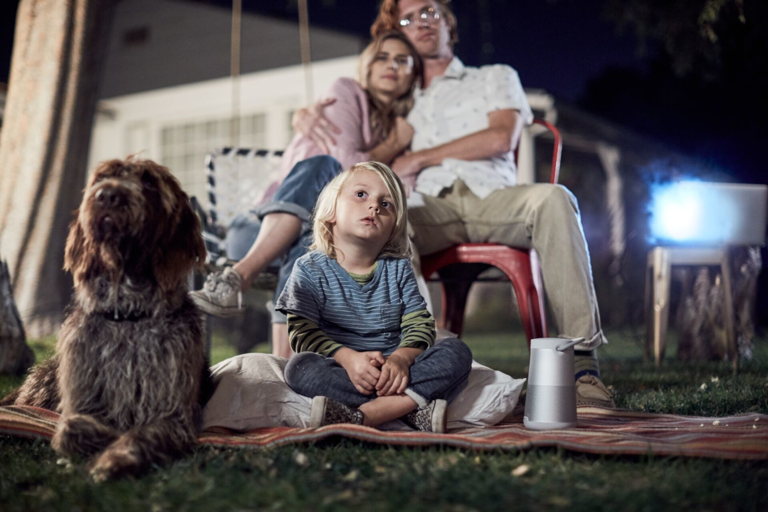 Familie die buiten een film bekijkt met een hond.
