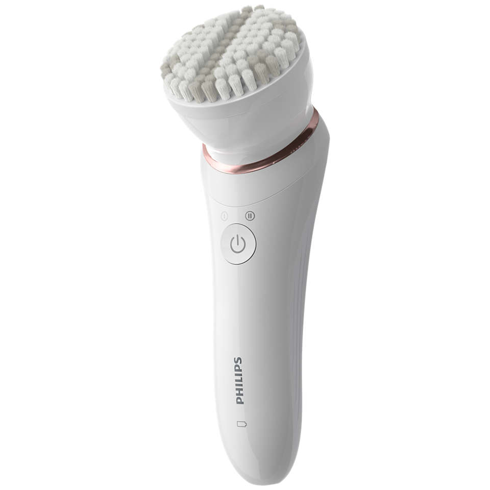 A white facial cleansing brush with a rose-gold ring. White background.