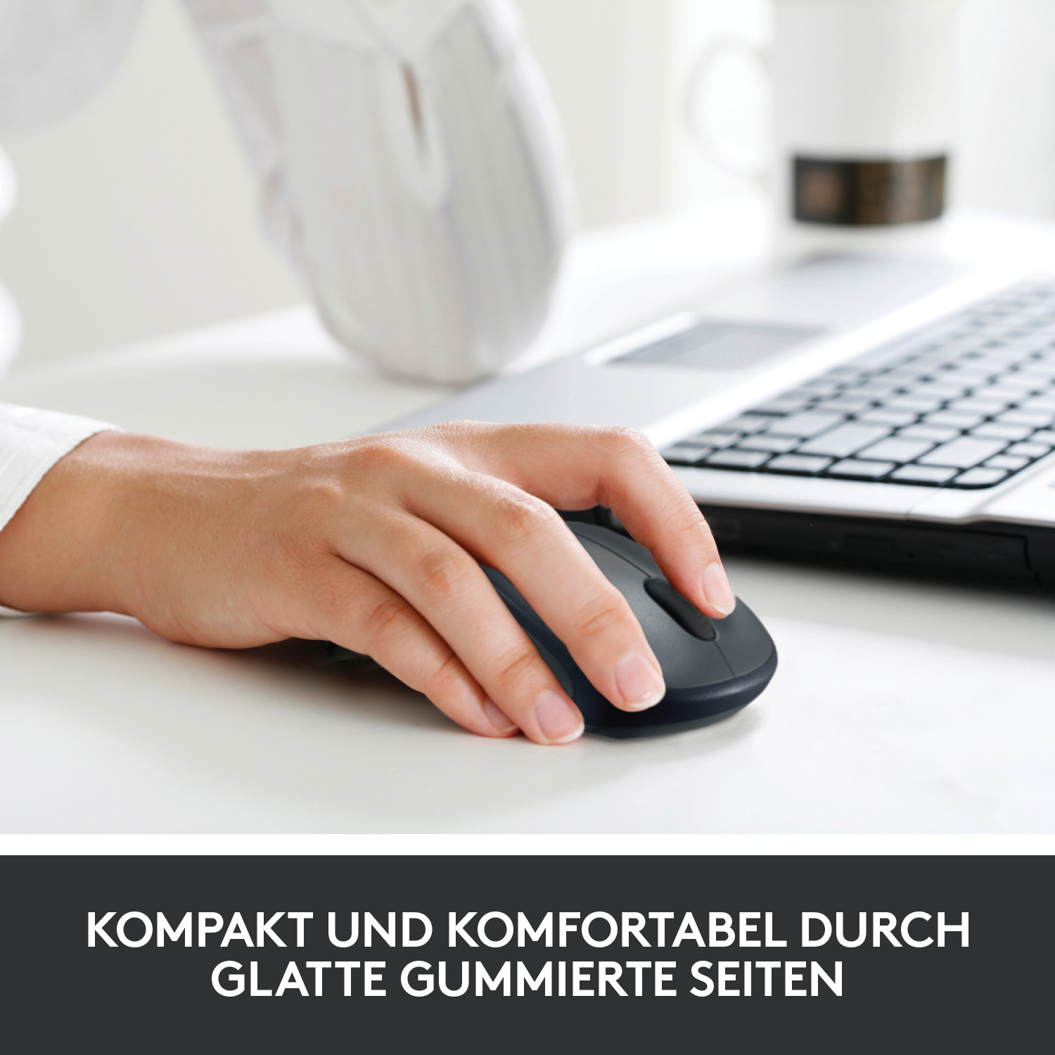 Eine Hand benutzt eine schwarze Logitech-Maus auf einem weißen Schreibtisch.