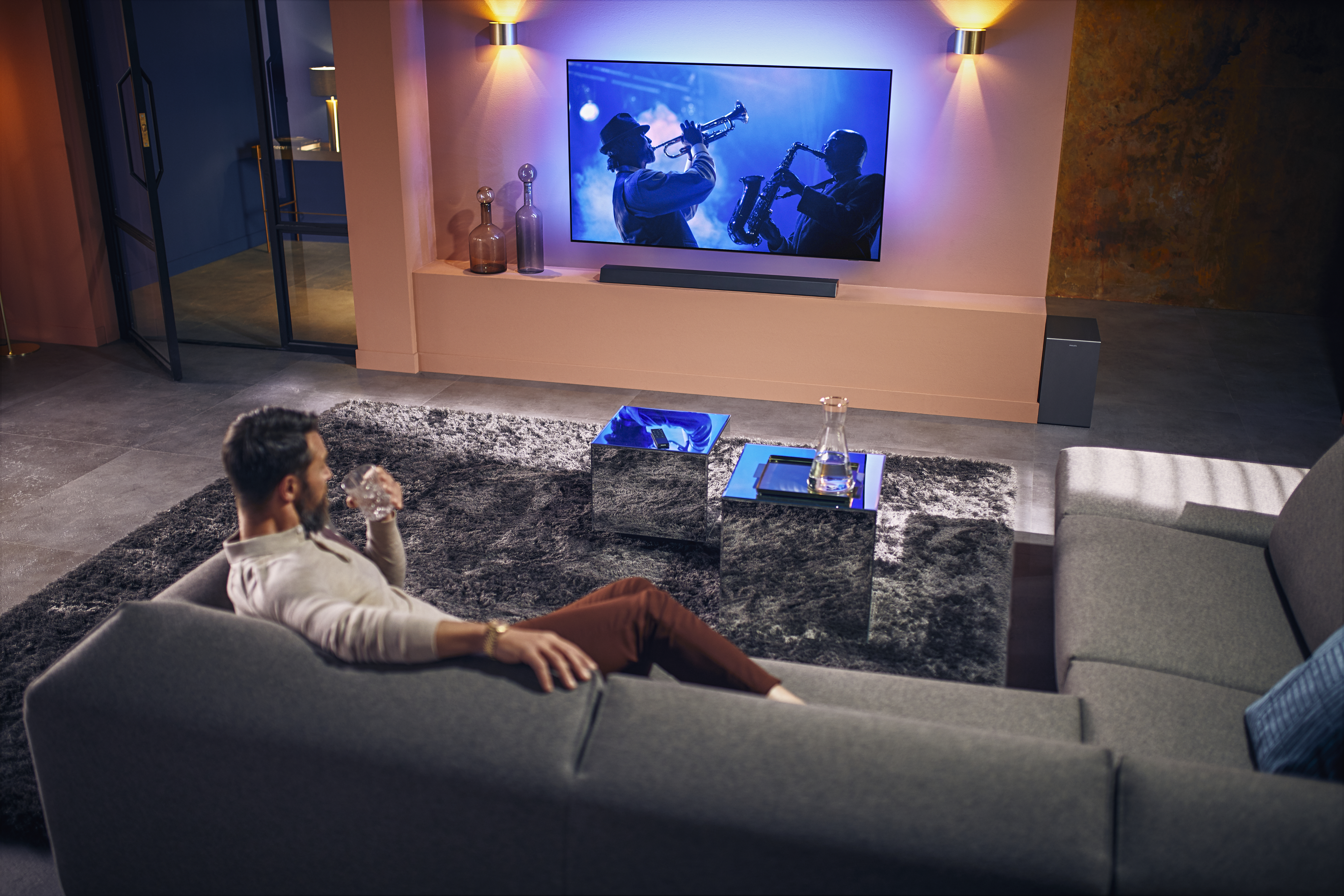 Ein Mann schaut im Wohnzimmer fern, moderne Einrichtung, Soundbar.