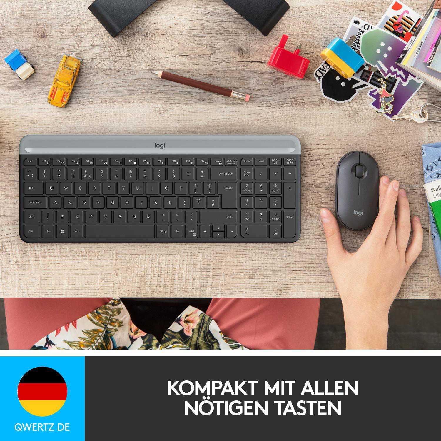 Tastatur und Maus auf einem Holztisch mit Spielzeug, Bleistift und Aufklebern.