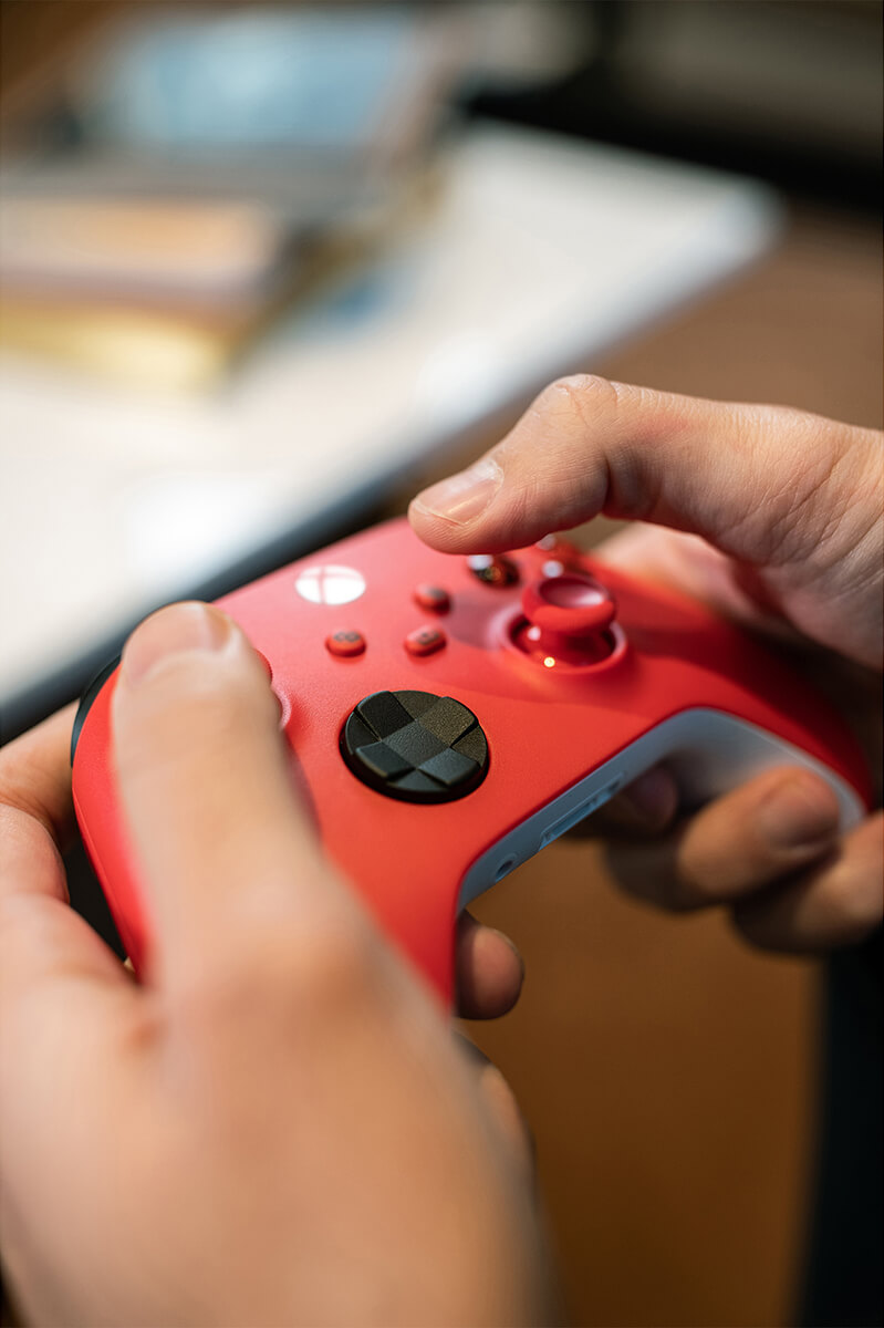 A person's hands holding a red gaming controller.