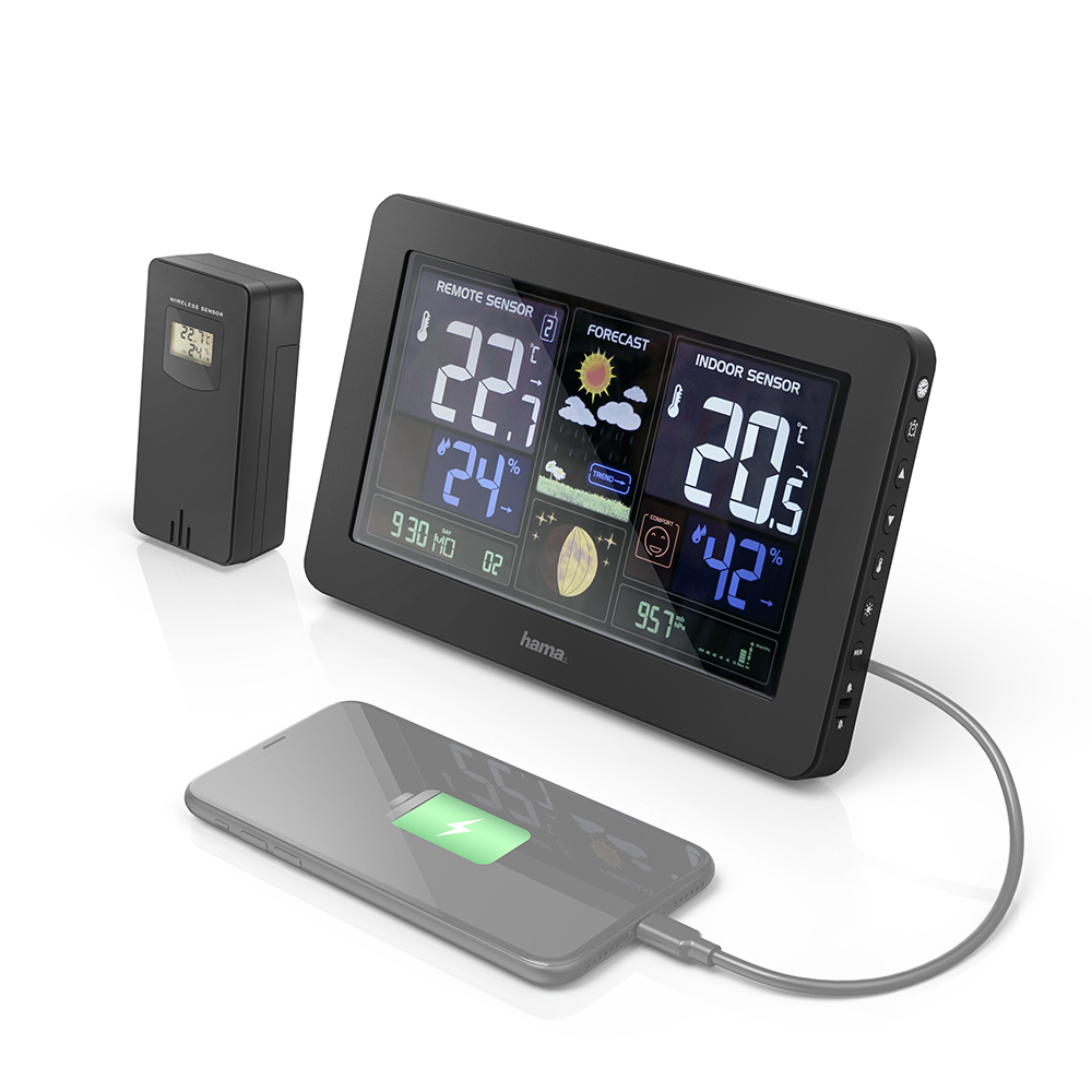 Black weather station displaying data, a wireless sensor, and a phone charging via a cable.