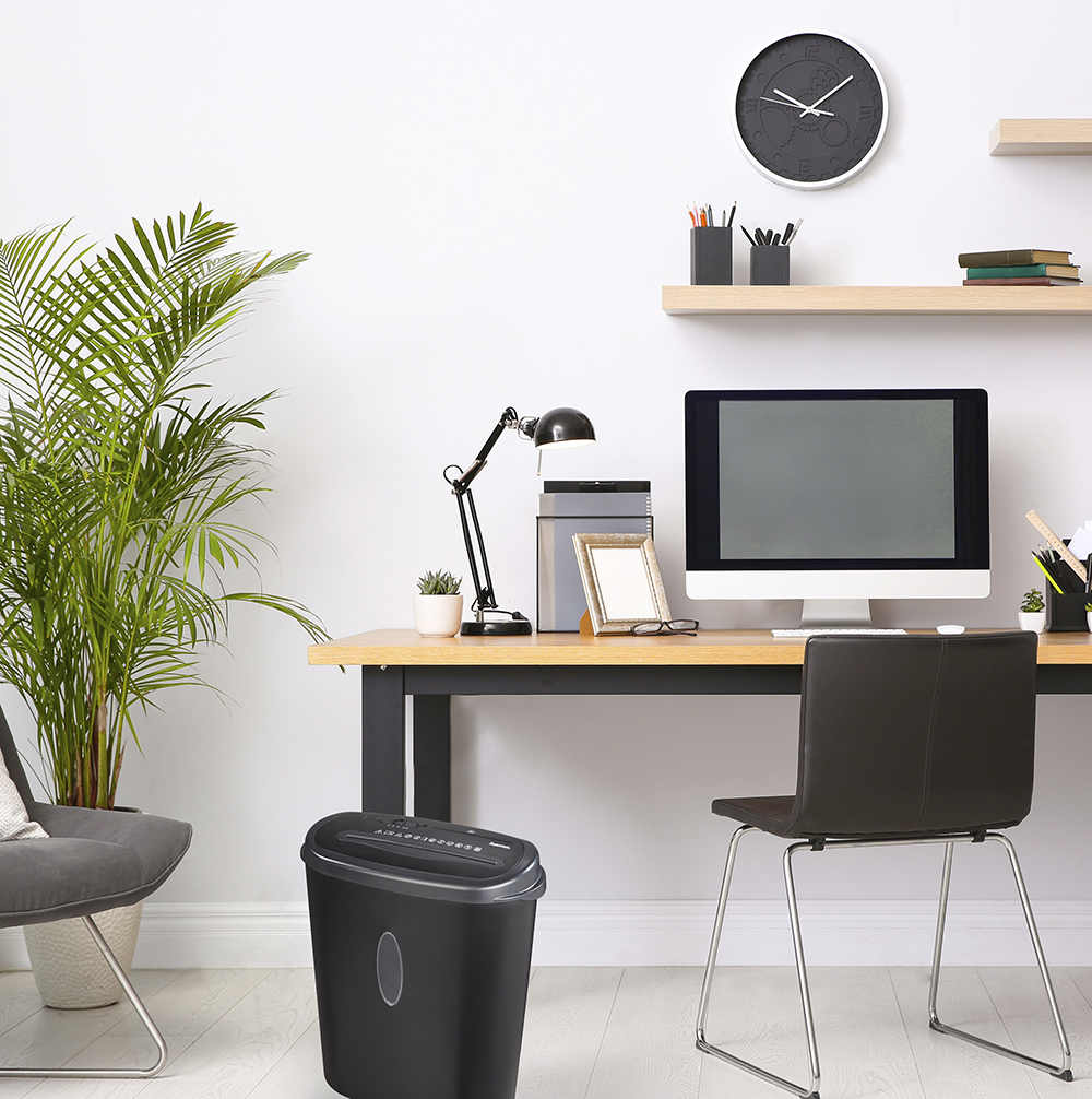Office desk with computer, shredder, plant, and lamp.