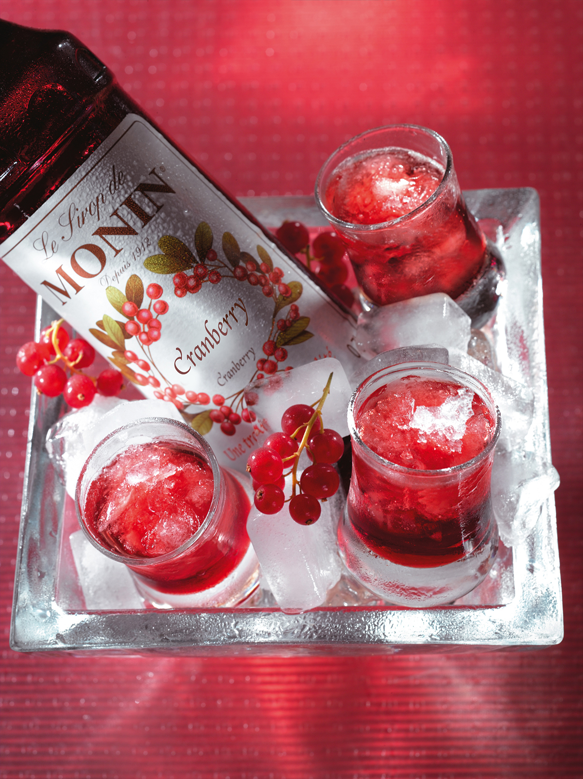 Cranberry-Sirup-Flasche mit Getränken und Eis.