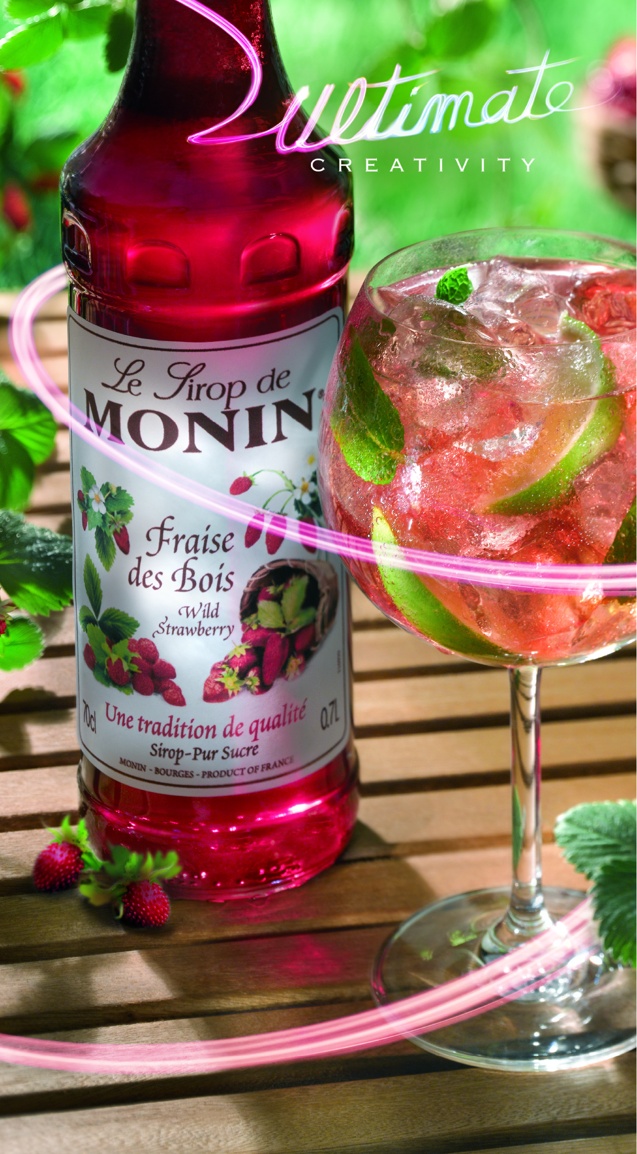 Eine Flasche Sirup neben einem Cocktail mit Limette.