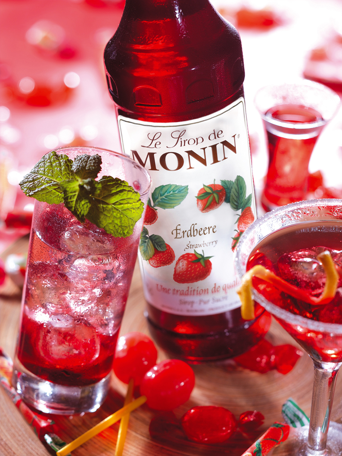 Erdbeersirup-Flasche und Getränke. Cocktails mit Erdbeeren und Minze.