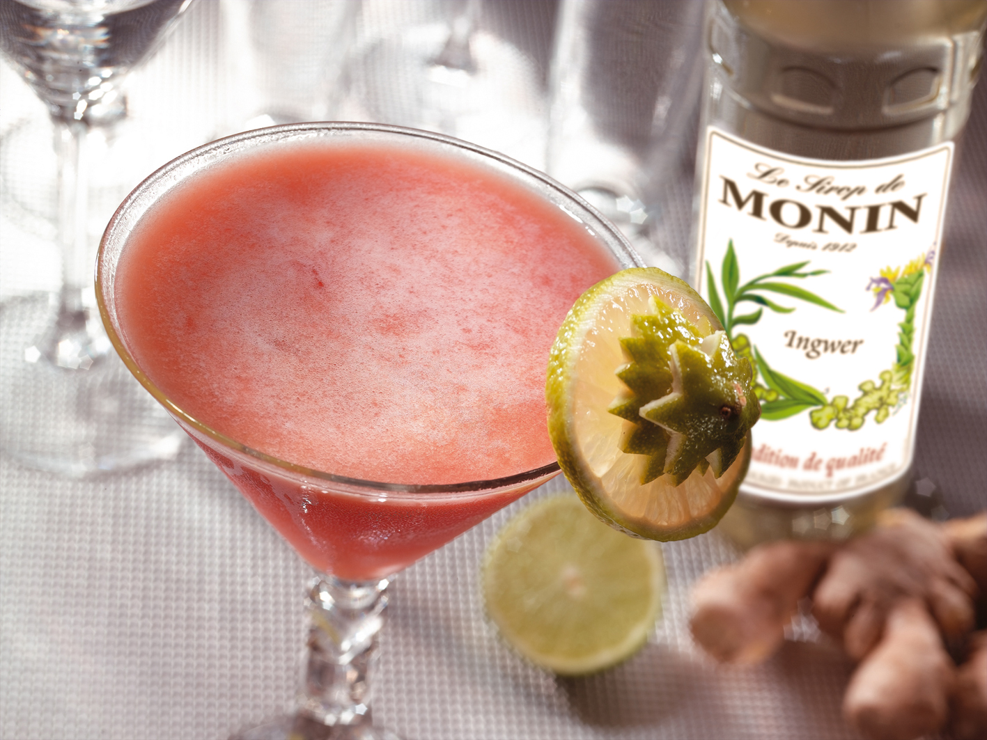 Cocktail in einem Martiniglas, garniert mit Limette und Monin-Sirup.