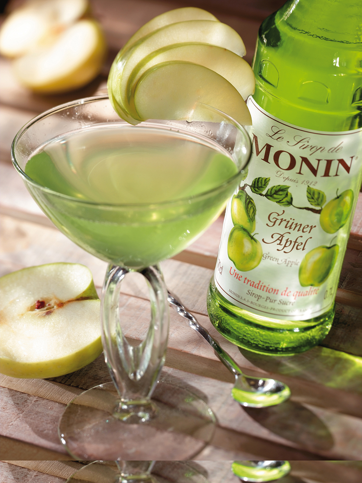 Grüner Apfel-Cocktail mit Monin-Sirup, Apfelscheiben und einem Cocktailglas.