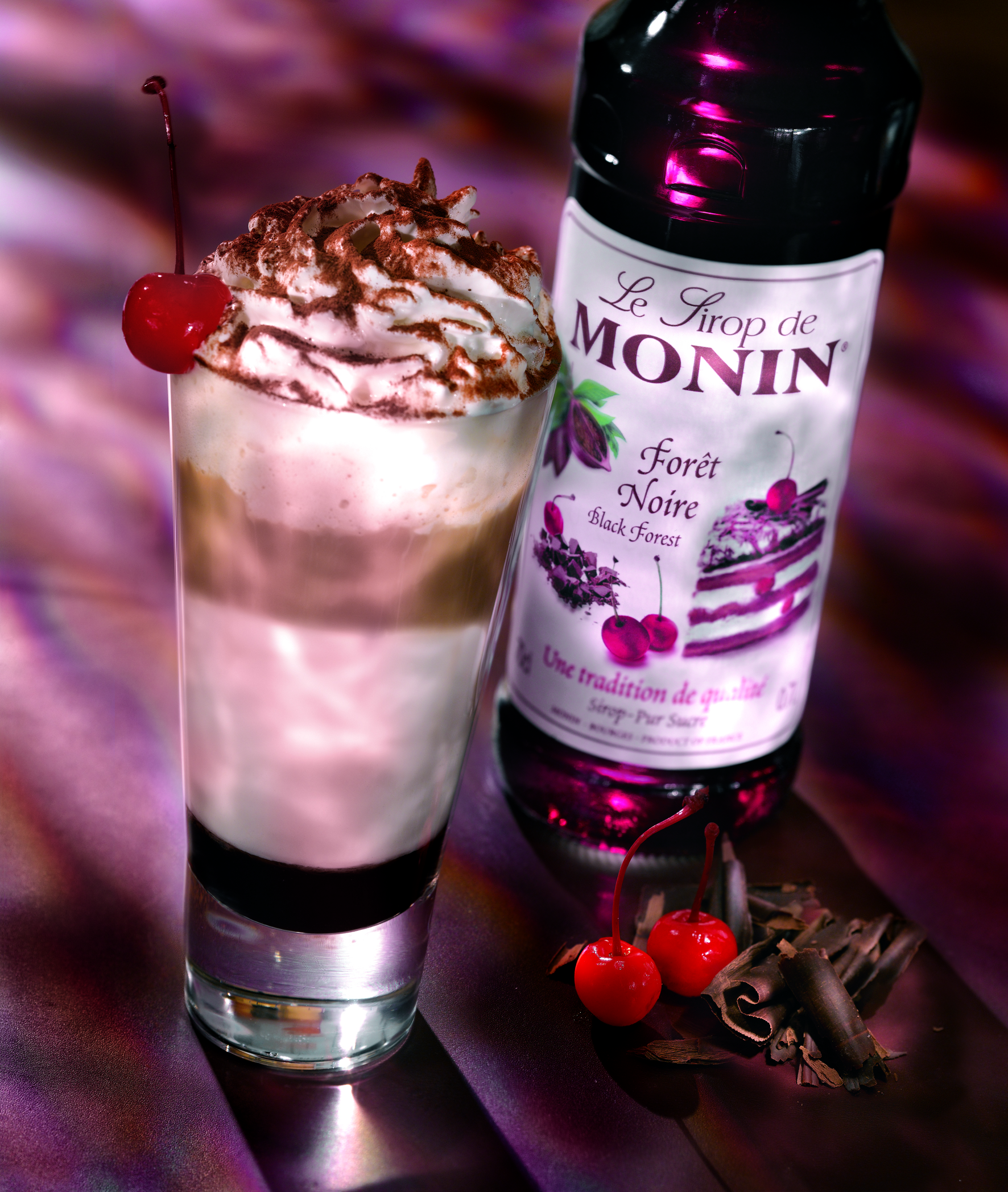 Schwarzwälder Cocktail mit Monin-Sirup, Kirschen und Schokoladenraspeln in einem hohen Glas.