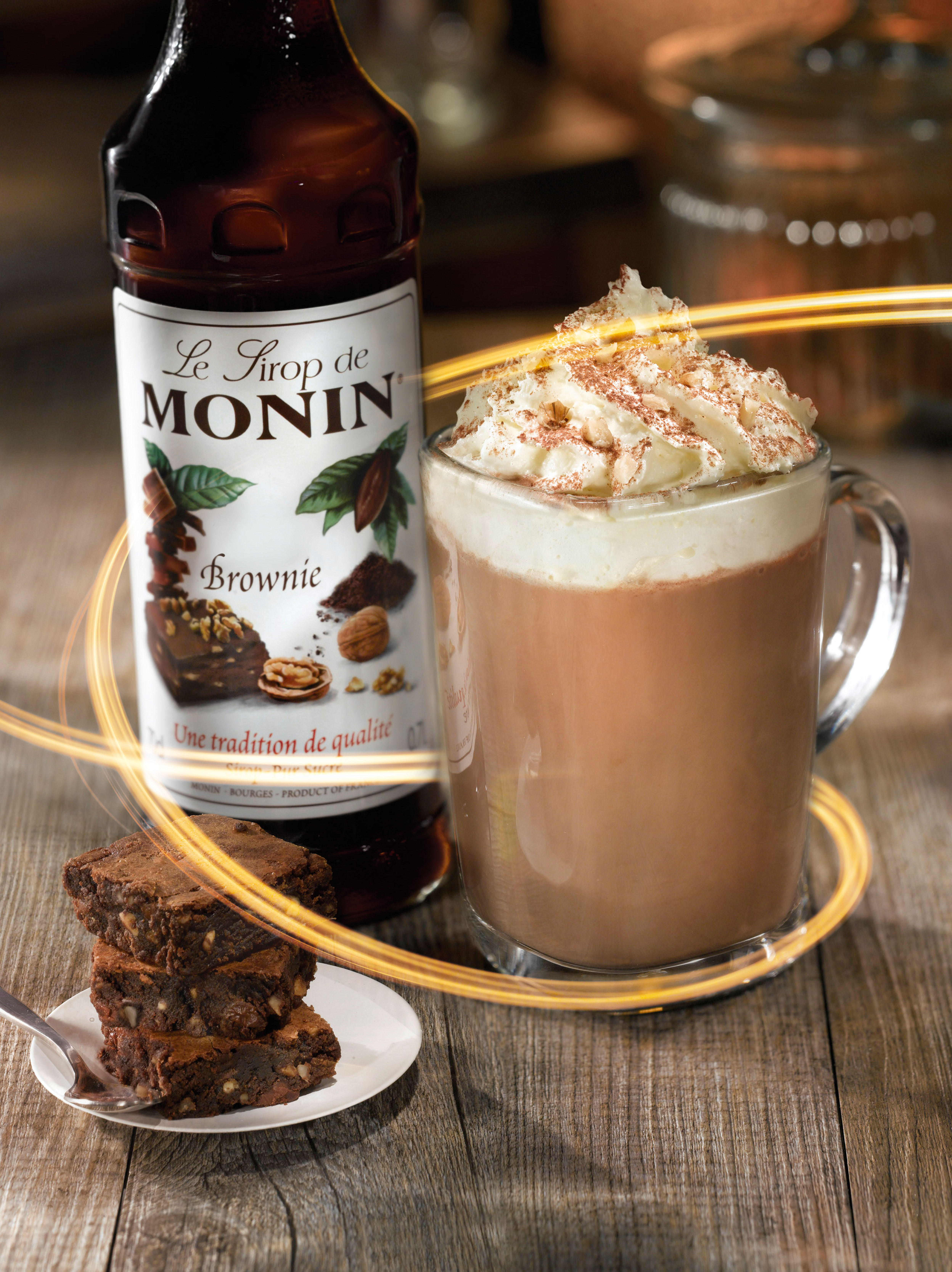 Brownie-Drink mit Schlagsahne. Brownies und Sirupflasche. Holztisch.