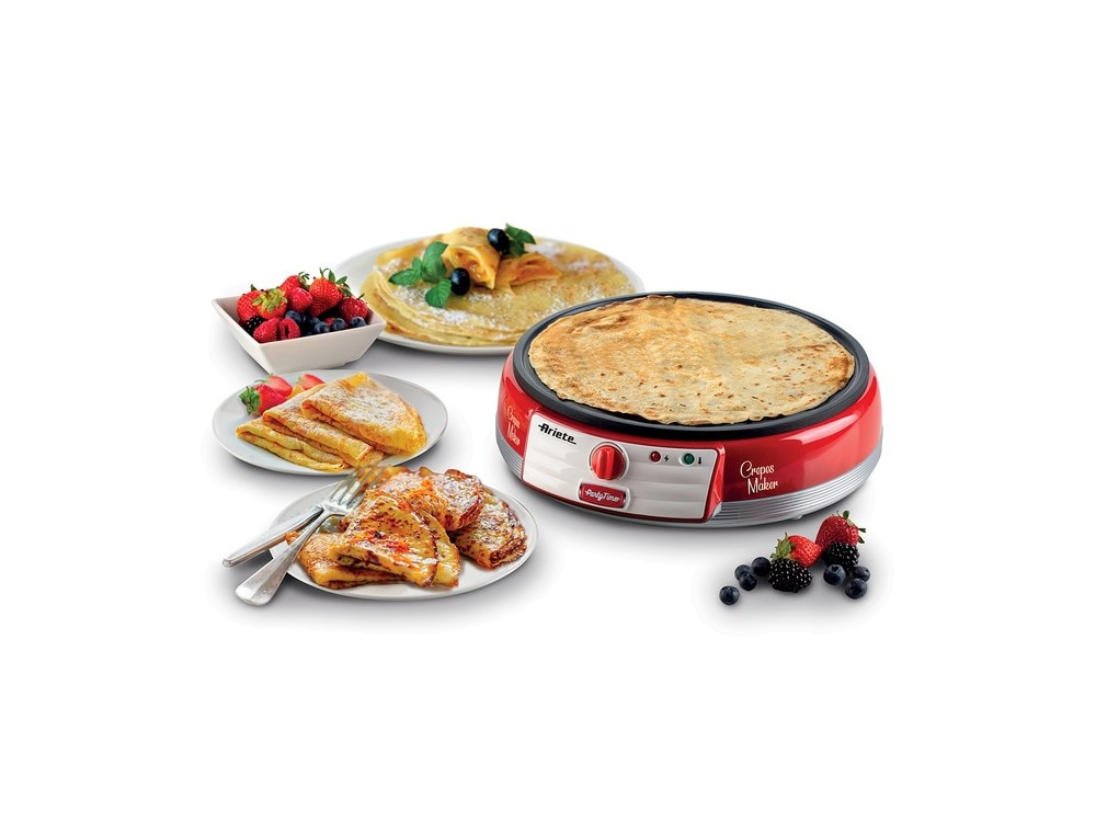 Máquina para crepes roja con crepes, frutas y panqueques en platos. Fondo blanco.