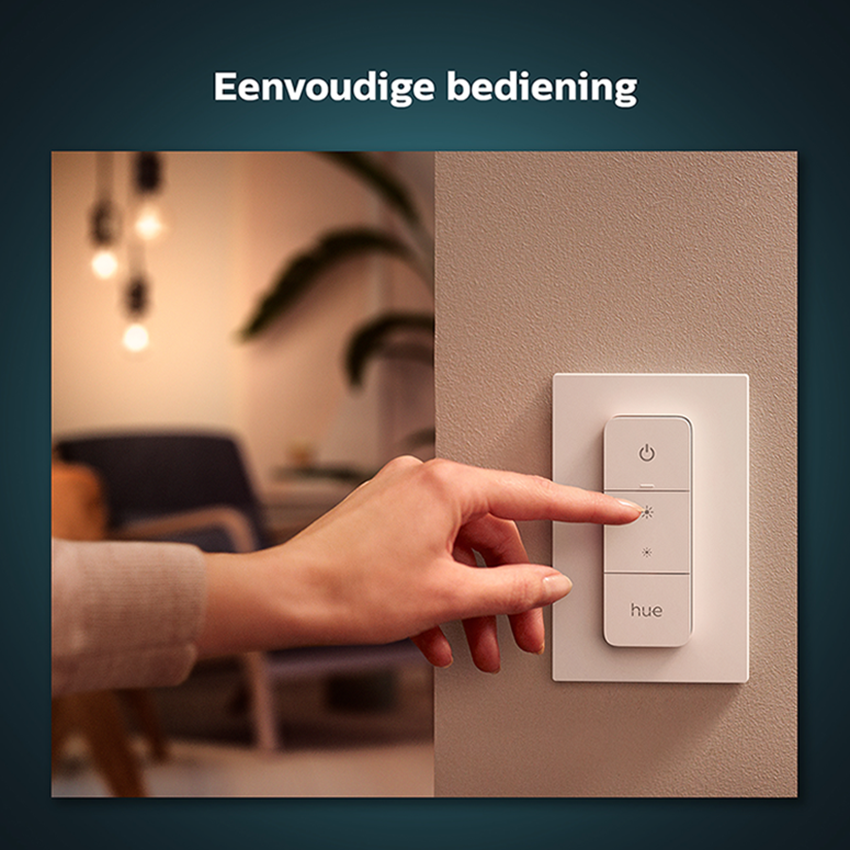 A person's hand presses a light switch on a wall.