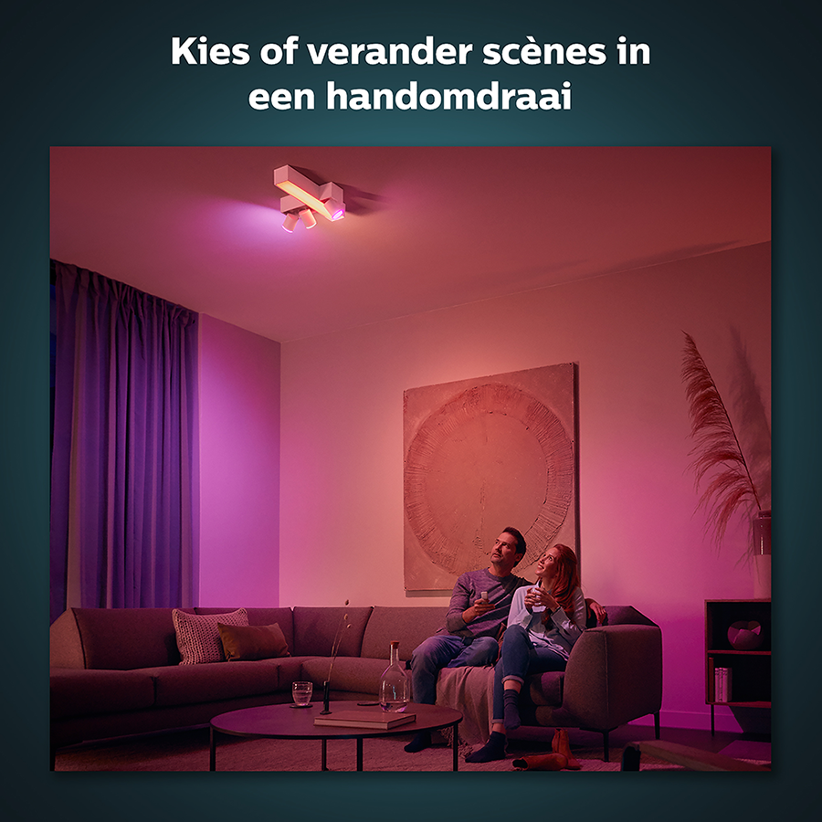 Couple sitting on a couch in a room with colored lights and a painting.