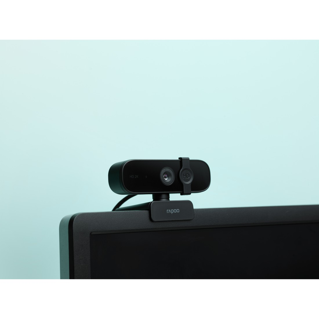 Schwarze Webcam auf einem Monitor. Die Webcam hat das Rapoo-Logo und einen hellblauen Hintergrund.