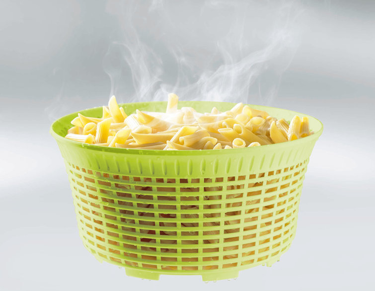 Dampfende Penne-Nudeln in einem grünen Abtropfsieb. Der Hintergrund ist hellgrau.