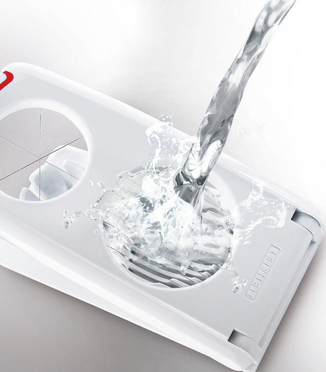 Ein weißer Eierschneider wird mit Wasser gewaschen und erzeugt Spritzer. Weißer Hintergrund.