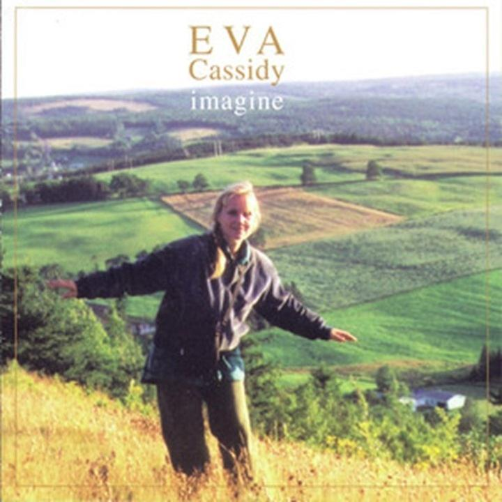 Eine Frau mit ausgestreckten Armen auf einem Hügel. Felder und Bäume im Hintergrund, mit dem Text 'EVA Cassidy imagine'.
