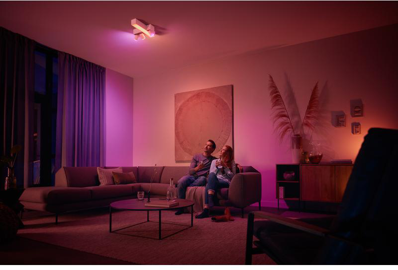 Wohnzimmer mit farbigen Lichtern. Ein Paar sitzt auf dem Sofa.