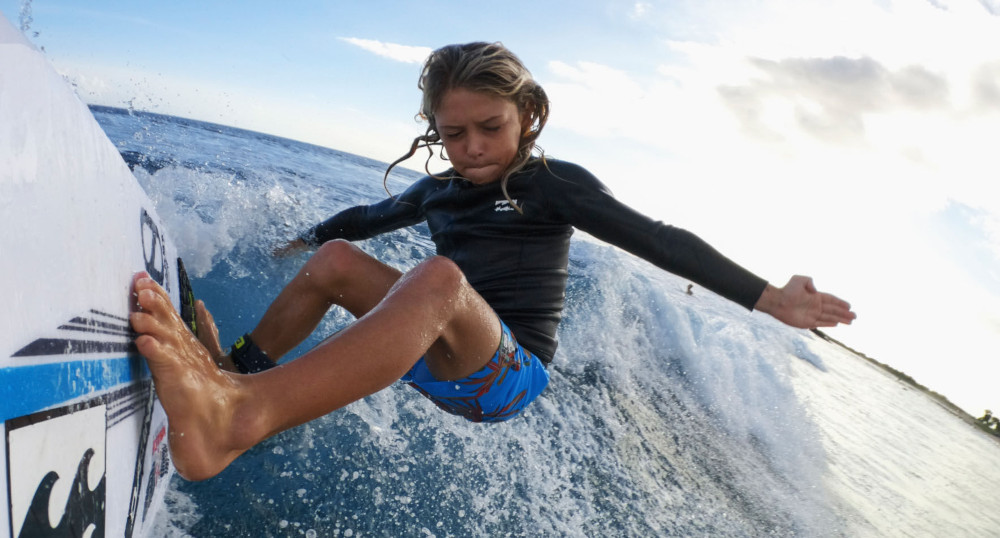 Un garçon sur une planche de surf, surfant une vague dans l'océan.