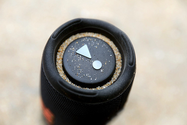 Close-up of a black speaker control panel with sand and buttons.