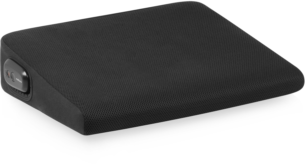 Un coussin noir en forme de coin avec une surface en forme de maille. Un petit panneau de contrôle est sur le côté gauche. Fond blanc.